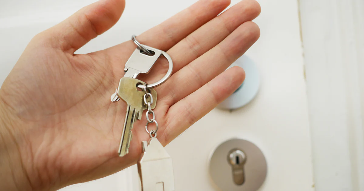 An open hand holding house keys in front of a door lock, representing getting control of your own website back